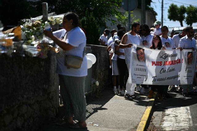 A person lays a flower outside the school next to Lyhanna's father and mother Martial Bernard (C) and Charly Rameau (3rdR) at the end of a silent march in tribute to Lyhanna, an 11-year-old girl found dead on June 4 after having been reported missing since May 29, in Fleurance, southwestern France, on June 7, 2026. Outrage has erupted in France after it emerged the main suspect Jerome.B, a 41-year-old father of two, had been repeatedly accused of sexually abusing children but no action was taken to protect others. The inscription on the jerseys reads : "Never again !". (Photo by Lionel BONAVENTURE / AFP)