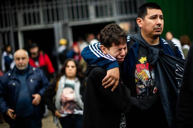 Fans react as they wait to pay their respects to the coffin with the remains of Carlos Alberto "Indio" Solari, the iconic Argentine rock musician and former lead singer of Patricio Rey y sus Redonditos de Ricota, at Villa Dominico, Buenos Aires Province, Argentina, on June 7, 2026. The singer died in Parque Leloir, Buenos Aires Province, on June 5 at the age of 77. (Photo by Tomas CUESTA / AFP)