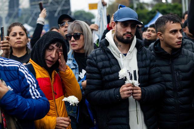 Fans react as they wait to pay their respects to the coffin with the remains of Carlos Alberto "Indio" Solari, the iconic Argentine rock musician and former lead singer of Patricio Rey y sus Redonditos de Ricota, at Villa Dominico, Buenos Aires Province, Argentina, on June 7, 2026. The singer died in Parque Leloir, Buenos Aires Province, on June 5 at the age of 77. (Photo by Tomas CUESTA / AFP)