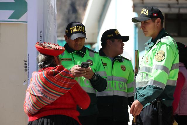 Police officers check a voter's information during the presidential election runoff at a polling station in Ollantaytambo, Cusco department, Peru, on June 7, 2026. Peruvians will choose their ninth president in 10 years in a tight runoff election between conservative Keiko Fujimori and leftist Roberto Sanchez, who are trying to woo voters fed up with political chaos and rising crime. (Photo by Jose Angulo / AFP)