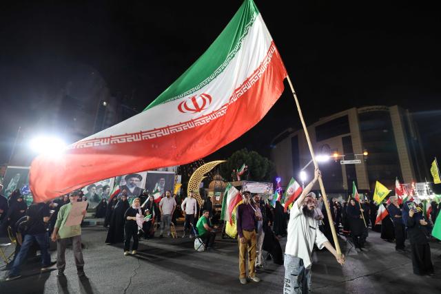Pro-government Iranian demonstrators wave flags of Iran and Lebanon's Hezbollah movement after Isreali strikes on Beirut's southern suburbs in Tehran on June 7, 2026. Air raid sirens sounded in Israel on Sunday as its military worked to intercept barrages of incoming Iranian missiles for the first time since an April ceasefire took hold in the Middle East war. Iran's powerful Revolutionary Guards called the attack a "warning" after Israel struck Beirut's southern suburbs earlier in the day, threatening wider strikes in the event of repeated aggression. (Photo by ATTA KENARE / AFP) / 