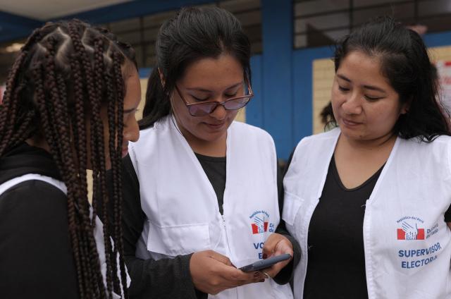Peruvian election supervisors check a cell phone during the vote counting of the presidential election runoff at a polling station in San Juan de Lurigancho district, province of Lima, Peru on June 7, 2026. Peruvians will choose their ninth president in 10 years, in a tight runoff election between conservative Keiko Fujimori and leftist Roberto Sanchez who are trying to woo voters fed up with political chaos and rising crime. (Photo by Anthony Nino de Guzman / AFP)