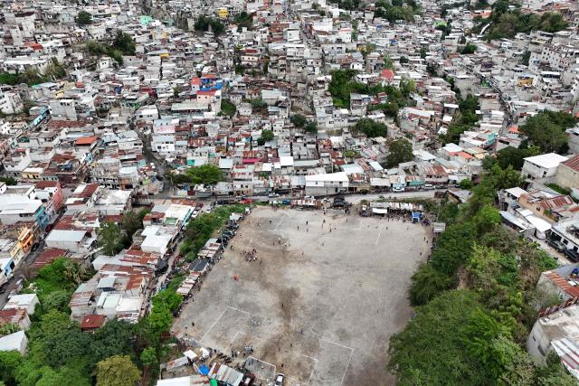 This aerial view shows the Maracana pitch in La Limonada neighbourhood in Guatemala City on June 7, 2026. Named after the iconic Maracana Stadium in Brazil, these dirt fields of the same name are a landmark of amateur football in Guatemala City. The Maracana pitch is located in an area that for years was marked by violence, bringing together players and fans from different neighborhoods of the capital every week. (Photo by Johan ORDÓÑEZ / AFP)