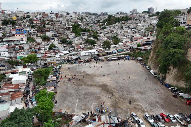 This aerial view shows the Maracana pitch in La Limonada neighbourhood in Guatemala City on June 7, 2026. Named after the iconic Maracana Stadium in Brazil, these dirt fields of the same name are a landmark of amateur football in Guatemala City. The Maracana pitch is located in an area that for years was marked by violence, bringing together players and fans from different neighborhoods of the capital every week. (Photo by Johan ORDÓÑEZ / AFP)