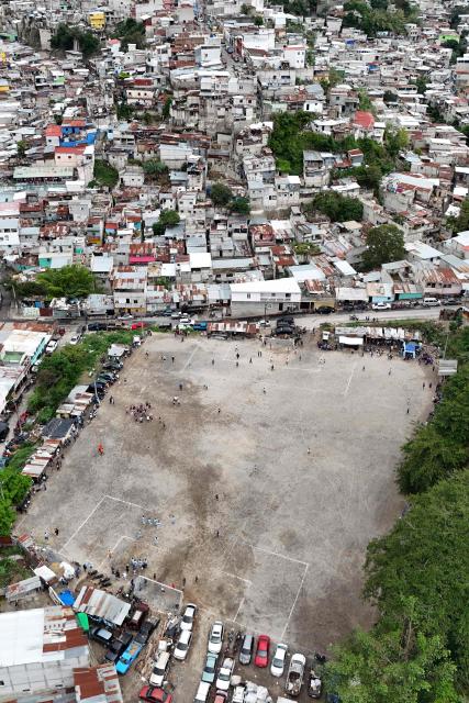 This aerial view shows the Maracana football pitch in La Limonada neighbourhood in Guatemala City on June 7, 2026. Named after the iconic Maracana Stadium in Brazil, these dirt fields of the same name are a landmark of amateur football in Guatemala City. The Maracana pitch is located in an area that for years was marked by violence, bringing together players and fans from different neighborhoods of the capital every week. (Photo by Johan ORDÓÑEZ / AFP)