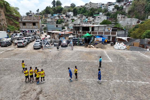 This aerial view shows people playing amateur football at the Maracana pitch in La Limonada neighbourhood in Guatemala City on June 7, 2026. Named after the iconic Maracana Stadium in Brazil, these dirt fields of the same name are a landmark of amateur football in Guatemala City. The Maracana pitch is located in an area that for years was marked by violence, bringing together players and fans from different neighborhoods of the capital every week. (Photo by Johan ORDÓÑEZ / AFP)