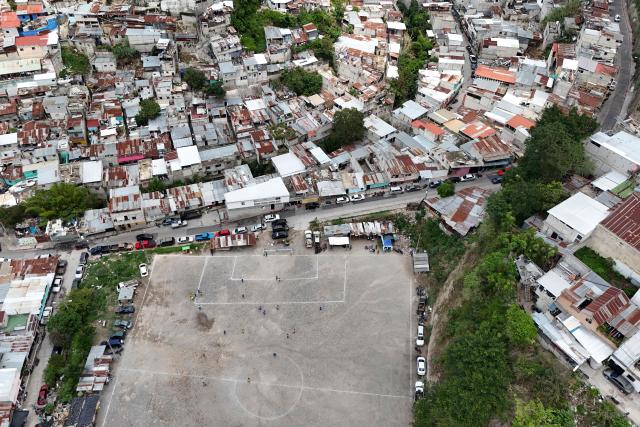 This aerial view shows the Maracana football pitch in La Limonada neighbourhood in Guatemala City on June 7, 2026. Named after the iconic Maracana Stadium in Brazil, these dirt fields of the same name are a landmark of amateur football in Guatemala City. The Maracana pitch is located in an area that for years was marked by violence, bringing together players and fans from different neighborhoods of the capital every week. (Photo by Johan ORDÓÑEZ / AFP)
