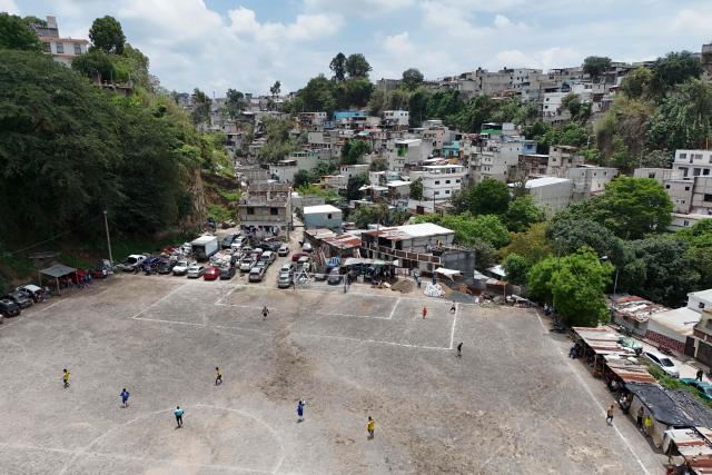 This aerial view shows people playing amateur football at the Maracana pitch in La Limonada neighbourhood in Guatemala City on June 7, 2026. Named after the iconic Maracana Stadium in Brazil, these dirt fields of the same name are a landmark of amateur football in Guatemala City. The Maracana pitch is located in an area that for years was marked by violence, bringing together players and fans from different neighborhoods of the capital every week. (Photo by Johan ORDÓÑEZ / AFP)