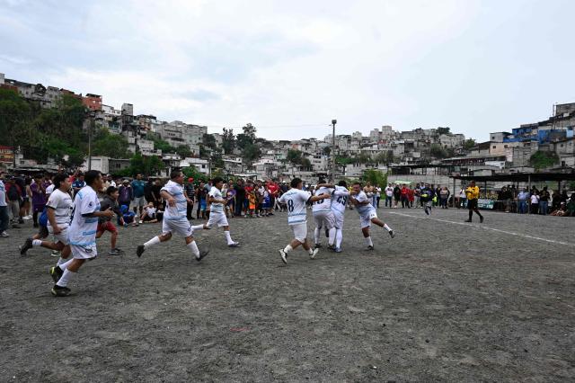 "Sportin" amateur football team players celebrate during a match at the Maracana pitch in La Limonada neighbourhood in Guatemala City on June 7, 2026. Named after the iconic Maracana Stadium in Brazil, these dirt fields of the same name are a landmark of amateur football in Guatemala City. The Maracana pitch is located in an area that for years was marked by violence, bringing together players and fans from different neighborhoods of the capital every week. (Photo by Johan ORDONEZ / AFP)