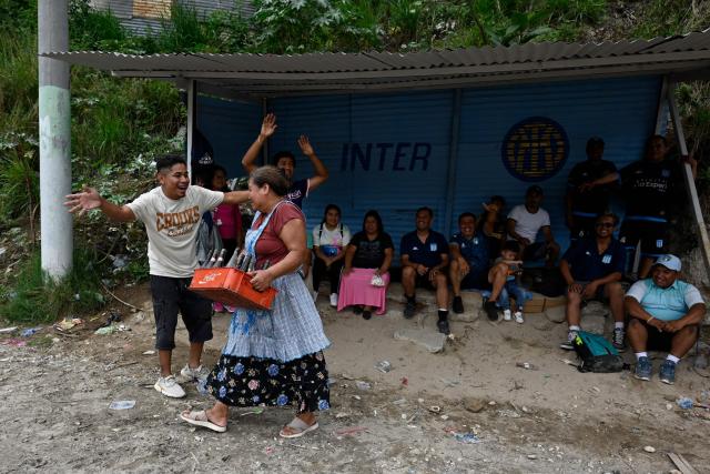 A woman hands out drinks during an amateur football match at the Maracana pitch in La Limonada neighbourhood in Guatemala City on June 7, 2026. Named after the iconic Maracana Stadium in Brazil, these dirt fields of the same name are a landmark of amateur football in Guatemala City. The Maracana pitch is located in an area that for years was marked by violence, bringing together players and fans from different neighborhoods of the capital every week. (Photo by Johan ORDONEZ / AFP)