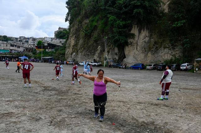 A woman spills a drink on the field during an amateur football match at the Maracana pitch in La Limonada neighbourhood in Guatemala City on June 7, 2026. Named after the iconic Maracana Stadium in Brazil, these dirt fields of the same name are a landmark of amateur football in Guatemala City. The Maracana pitch is located in an area that for years was marked by violence, bringing together players and fans from different neighborhoods of the capital every week. (Photo by Johan ORDONEZ / AFP)