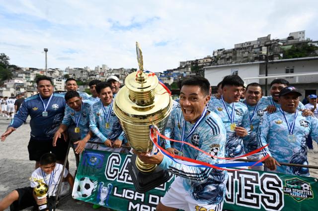 "Lourdes II" amateur football team players lift the trophy after winning a tournament at the Maracana pitch in La Limonada neighbourhood in Guatemala City on June 7, 2026. Named after the iconic Maracana Stadium in Brazil, these dirt fields of the same name are a landmark of amateur football in Guatemala City. The Maracana pitch is located in an area that for years was marked by violence, bringing together players and fans from different neighborhoods of the capital every week. (Photo by Johan ORDONEZ / AFP)