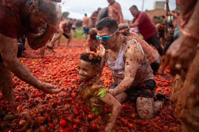 A man grabs a child during the 16th Tomato Fight Festival known as "Tomatina" in Sutamarchan, Boyaca department, Colombia on June 7, 2026. (Photo by ESTEBAN VEGA LA-ROTTA / AFP)