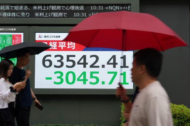 Pedestrians walk in front an electronic quotation board displaying the Nikkei Stock Average on the Tokyo Stock Exchange along a street in Tokyo on June 8, 2026. (Photo by Kazuhiro NOGI / AFP)
