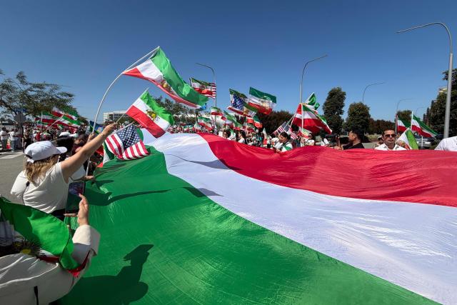 People wave US and pre-revolutionary Iranian flags as they protest the Iranian regime outside of Los Angeles Stadium (temporarly renamed from SoFi Stadium) in Inglewood, California, on June 7, 2026, ahead of the start of the 2026 FIFA World Cup. Iran are scheduled to open their Group G campaign against New Zealand in Los Angeles on June 15, before facing Belgium in the same city and then Egypt in Seattle. (Photo by Sarah LAI / AFP)