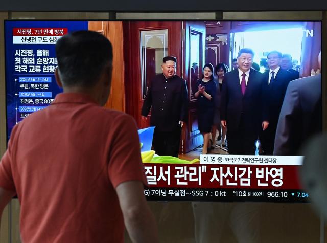 A man walks past a television screen showing a news broadcast with file footage of the 2019 meeting between China's President Xi Jinping and North Korean leader Kim Jong Un, at a train station in Seoul on June 8, 2026. China's President Xi Jinping hailed an "invincible friendship" with Pyongyang as he arrived in North Korea on June 8, his first trip abroad this year after hosting back-to-back summits in Beijing. (Photo by Jung Yeon-je / AFP)