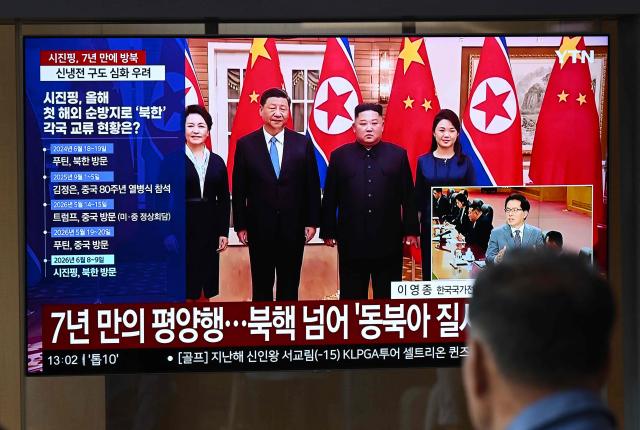 A man watches a television screen showing a news broadcast with file footage of the 2019 meeting between China's President Xi Jinping and North Korean leader Kim Jong Un, at a train station in Seoul on June 8, 2026. China's President Xi Jinping hailed an "invincible friendship" with Pyongyang as he arrived in North Korea on June 8, his first trip abroad this year after hosting back-to-back summits in Beijing. (Photo by Jung Yeon-je / AFP)