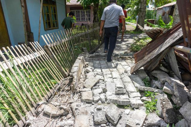 People past damage in a residential area caused by a magnitude 7.8 earthquake off the southern Philippines, at Peta Timur village in Sangihe Islands Regency, Indonesia's North Sulawesi province on June 8, 2026. The quake which killed at least three people in the Philippines triggered evacuation warnings for coastal areas of neighbouring Indonesia and Malaysia, with Jakarta's meteorological agency subsequently lifting its alert. (Photo by Stenly Pontolawokang / AFP)