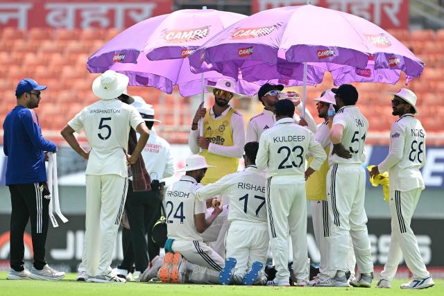 Indian cricket team players take a drinks-break under the umbrellas during the third day of the only Test cricket match between India and Afghanistan at the Maharaja Yadavindra Singh International Cricket Stadium on the outskirts of Chandigarh on June 8, 2026. (Photo by Shammi MEHRA / AFP)