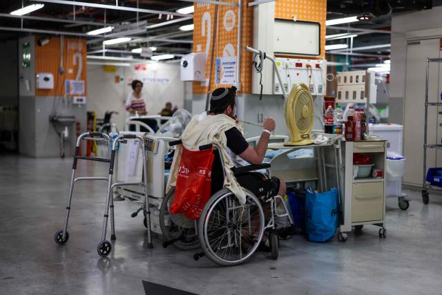 A patient sitting in a wheelchair prays after being moved to an underground hospital facility for safety in Tel Aviv on June 8, 2026, after sirens sounded following Iranian attacks. Israel and Iran traded fire on June 8, seriously testing a fragile truce and threating hopes for a deal to end the Middle East war. (Photo by Ilia YEFIMOVICH / AFP)