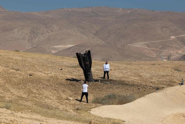 A man poses for a photos next to a fallen rock half-buried in the ground on the outskirts of Jericho on June 8, 2026, following Iranian and Iran-backed Houthi rebel attacks. Israel and Iran traded fire on June 8, seriously testing a fragile truce and threating hopes for a deal to end the Middle East war. (Photo by Ahmad GHARABLI / AFP) / 
