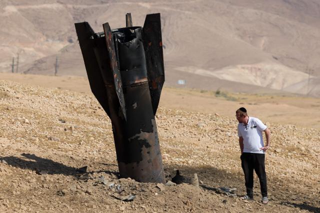 TOPSHOT - A man checks a fallen rock half-buried in the ground on the outskirts of Jericho on June 8, 2026, following Iranian and Iran-backed Houthi rebel attacks. Israel and Iran traded fire on June 8, seriously testing a fragile truce and threating hopes for a deal to end the Middle East war. (Photo by Ahmad GHARABLI / AFP) / 