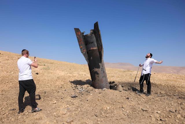 TOPSHOT - A man poses for a photo next to a fallen rock half-buried in the ground on the outskirts of Jericho on June 8, 2026, following Iranian and Iran-backed Houthi rebel attacks. Israel and Iran traded fire on June 8, seriously testing a fragile truce and threating hopes for a deal to end the Middle East war. (Photo by AHMAD GHARABLI / AFP) / 