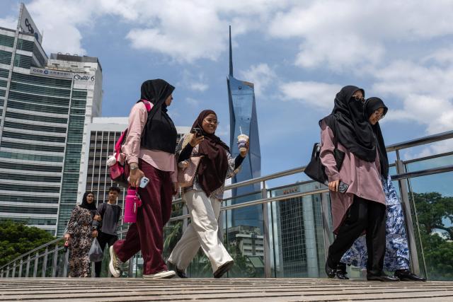 Women walk along a pedestrian bridge with the Warisan Merdeka Tower (KL118), the world's second-tallest building, looming in the background in Kuala Lumpur on June 8, 2026. (Photo by Mohd RASFAN / AFP)