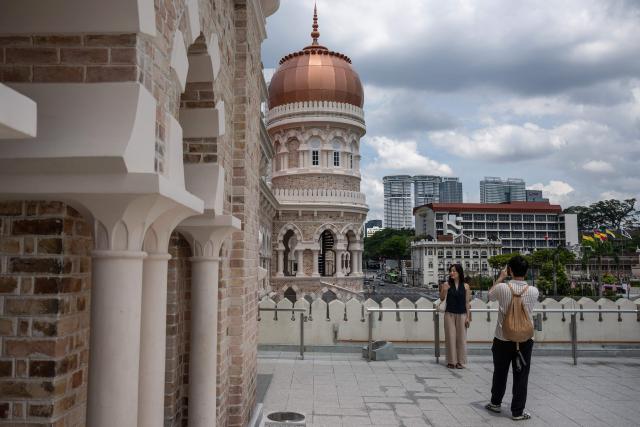 Tourists take pictures with the Sultan Abdul Samad building near Merdeka Square in Kuala Lumpur on June 8, 2026. (Photo by Mohd RASFAN / AFP)