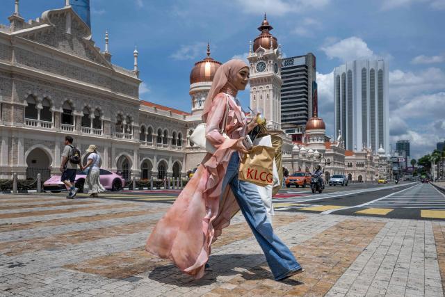 A woman crosses the street in front of the Sultan Abdul Samad building near Merdeka Square in Kuala Lumpur on June 8, 2026. (Photo by Mohd RASFAN / AFP)
