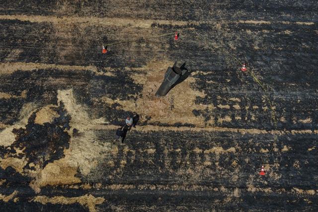 This aerial view shows Syrian farmers standing next to an Iranian missile that fell into an agricultural land in the area of Najha, in the countryside of the Syrian capital after being intercepted by Israeli air defense systems on June 8, 2026. Iraq and Syria closed their airspace as a safety precaution on June 7 after their eastern neighbour Iran launched missiles across their territory towards targets in Israel. In a brief statement, the Iraqi Civil Aviation Authority reported the closure of Iraqi airspace for 72 hours. Syria's authority closed the country's "southern air corridors" for 12 hours. (Photo by Bakr ALKASEM / AFP)