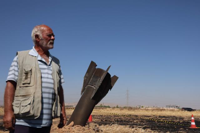 A Syrian farmer stands next to an Iranian missile that fell into an agricultural land in the area of Najha, in the countryside of the Syrian capital after being intercepted by Israeli air defense systems on June 8, 2026. Iraq and Syria closed their airspace as a safety precaution on June 7 after their eastern neighbour Iran launched missiles across their territory towards targets in Israel. In a brief statement, the Iraqi Civil Aviation Authority reported the closure of Iraqi airspace for 72 hours. Syria's authority closed the country's "southern air corridors" for 12 hours. (Photo by Bakral-KASSEM / AFP)