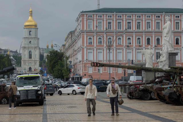 Men wearing embroidered shirts and with a military helmet arrive for the funeral ceremony of Yaroslav Varnak, a 23 years old serviceman who was killed in action in Kyiv on June 8, 2026, amid the Russian invasion of Ukraine. (Photo by Tetiana DZHAFAROVA / AFP)