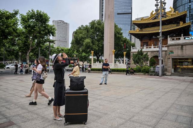 A woman prays in front of Jing'an Temple in the Jing' an district of Shanghai on June 8, 2026. (Photo by HECTOR RETAMAL / AFP)