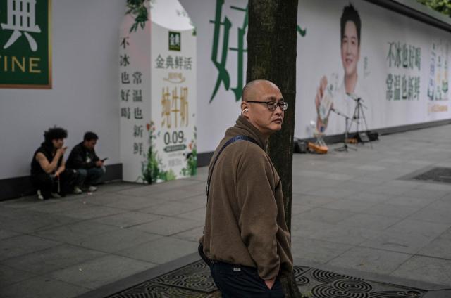 A man looks on as he walks down a street in the Jing' an district of Shanghai on June 8, 2026. (Photo by HECTOR RETAMAL / AFP)