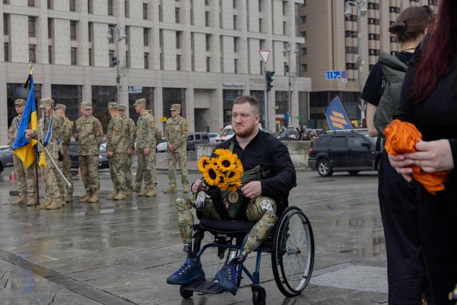A man holds flowers during the funeral ceremony of Yaroslav Varnak, a 23 years old serviceman who was killed in action in Kyiv on June 8, 2026, amid the Russian invasion of Ukraine. (Photo by Tetiana DZHAFAROVA / AFP)