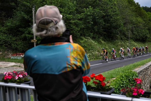 A spectator photographs the lead breakaway as it cycles during the 2nd stage of the Tour Auvergne-Rhone-Alpes cycling race (formerly known as the Criterium du Dauphine), 234,3km between Saint-Martin-Le-Vinoux in the French Alps and Le Puy-en-Velay near the Massif Central, on June 8, 2026. (Photo by Anne-Christine POUJOULAT / AFP)