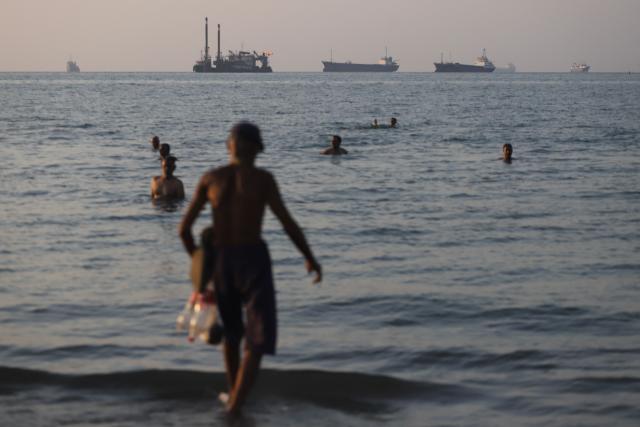 In this picture obtained from Iran's ISNA news agency on June 8, 2026, residents take a dip as cargo and commercial vessels lie at anchor in the Strait of Hormuz off Bandar Abbas. Iran on June 8 said it was ending its latest military operation against Israel after the first exchanges of fire between the foes since a shaky ceasefire began, but warned it could inflict a more "crushing" response. Iran fired dozens of missiles at Israel overnight and Israel responded by targeting military sites in the Islamic republic, sparking fears the escalation could usher in a new full-scale conflict after the April 8 truce. (Photo by Amirhossein KHORGOOEI / ISNA / AFP) / 