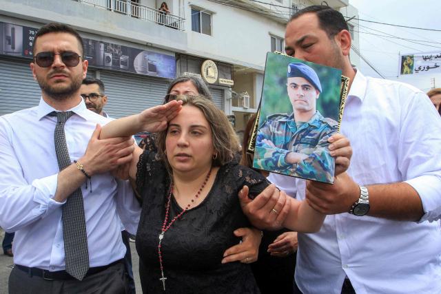 EDITORS NOTE: Graphic content / Rosette Tannous, wife of Lebanese army captain Elie Khoury who was killed by Israeli bombardment, salutes as mourners carry her husband's coffin past during the funeral in his home village of Kfar Jarra near Jezzine in southern Lebanon on June 8, 2026. An Israeli strike in southern Lebanon killed three soldiers, Beirut's military said on June 6, as its chief travelled to Pakistan to meet with a key mediator in efforts to end the Middle East war. Israel has launched an operation in Lebanon to root out the Tehran-backed armed group Hezbollah, which drew Lebanon into the wider Middle East war by launching missiles on behalf of its sponsor. (Photo by Mahmoud ZAYYAT / AFP)