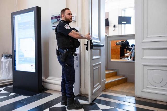 A French police officer stands guard at the door of a courtroom at the Saint-Omer Judicial Court in Saint-Omer, northern France, on June 8, 2026. The trial of a man accused of ruling his home with terror for two decades, where he lived with three women and their children, opened on June 8, 2026, in the Pas-de-Calais. The defendant denies any violence but acknowledges a “bizarre” family dynamic. (Photo by Sameer Al-DOUMY / AFP)