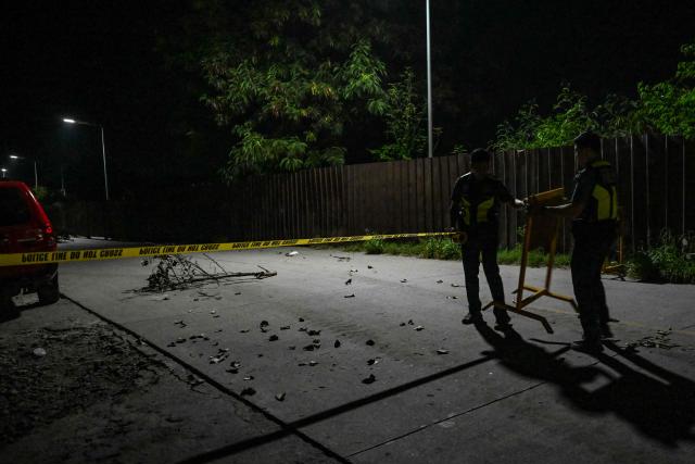 Policemen secure the road outside a collapsed building after a 7.8 magnitude earthquake in General Santos City on June 8, 2026. The earthquake in the southern Philippines killed at least 31 people, according to provincial authorities, after toppling buildings and sparking tsunami warnings across the region. (Photo by Jam STA ROSA / AFP)