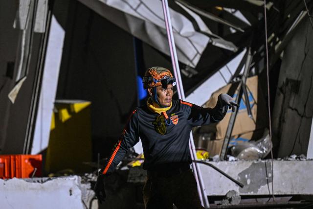 A responder gestures while assessing a collapsed building after a 7.8 magnitude earthquake in General Santos City on June 8, 2026. The earthquake in the southern Philippines killed at least 31 people, according to provincial authorities, after toppling buildings and sparking tsunami warnings across the region. (Photo by Jam STA ROSA / AFP)