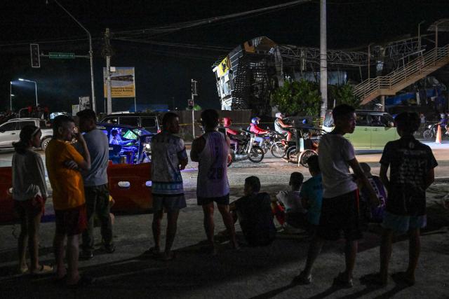 People observe the rescue operations outside a collapsed building after a 7.8 magnitude earthquake in General Santos City on June 8, 2026. The earthquake in the southern Philippines killed at least 31 people, according to provincial authorities, after toppling buildings and sparking tsunami warnings across the region. (Photo by Jam STA ROSA / AFP)