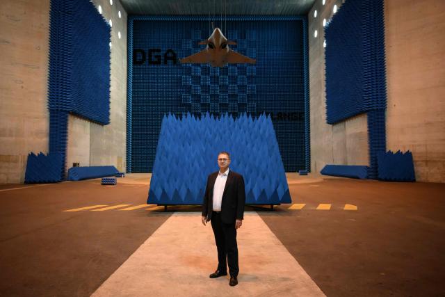 French Director of the Center for Expertise and Testing of the DGA MI Frederic Bouyer poses under a Rafale F4 fighter aircraft hanging in the SOLANGE (Systeme Orientable Lourd pour Aeronefs et Gros Engins) room of the DGA (Direction Generale de l'Armement) Maitrise de l'Information (MI) in Bruz, western France, on June 8, 2026. The Solange facility is dedicated to evaluating the radar signature of full-scale aircraft, such as the Rafale, or large missiles. These measures make it possible to evaluate aircraft in the face of the various radar threats they may encounter in an operational configuration. (Photo by Loic VENANCE / AFP)