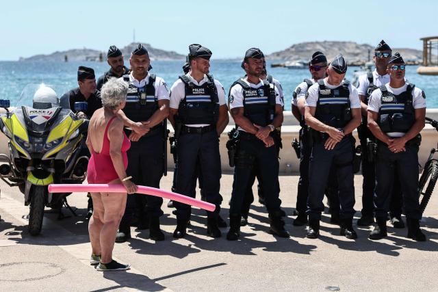 A beach goer speaks to police officers gathering along the promenade in Catalans beach during the prefecture’s press conference to announce of security measures implemented on Marseille’s beaches, in southeastern France, on June 8, 2026. (Photo by Thibaud MORITZ / AFP)