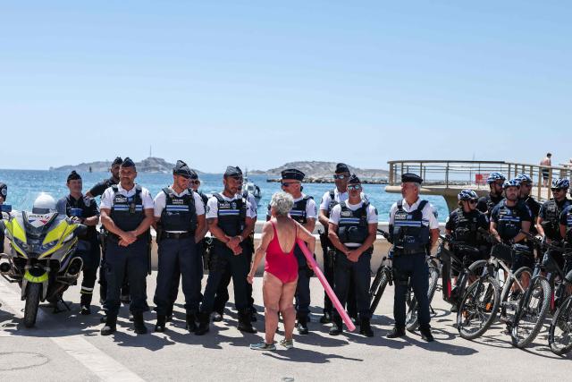 A beach goer speaks to police officers gathering along the promenade in Catalans beach during the prefecture’s press conference to announce of security measures implemented on Marseille’s beaches, in southeastern France, on June 8, 2026. (Photo by Thibaud MORITZ / AFP)