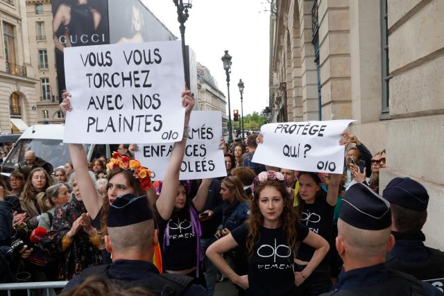 Members of international radical feminist activist group FEMEN take part in an unauthorised demonstration near Place Vendome outside the French Justice Ministry in Paris on June 8, 2026, at the call of the Mouv'Enfants collective and other organisations, to demand a law against violence on minors, following the death of Lyhanna, an 11-year-old girl found dead on June 4 after being reported missing on May 29 in southwestern France, on June 8, 2026. The placard reads "You wipe your ass with our complaints" (L). (Photo by GEOFFROY VAN DER HASSELT / AFP)