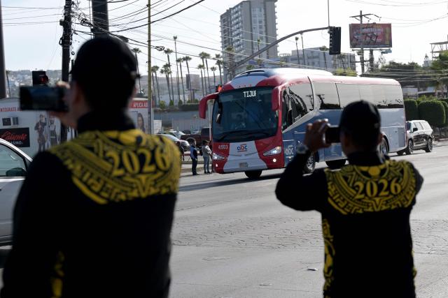 Members of Mexico's National Guard record with their mobile phones the arrival of the bus transporting Iran's national football team at the Caliente Stadium for a training session in Tijuana, Mexico, on June 8, 2026, ahead of the FIFA 2026 World Cup football tournament. (Photo by Guillermo Arias / AFP)