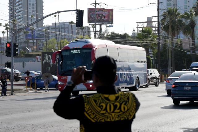 A member of Mexico's National Guard records with a mobile phone the arrival of the bus transporting Iran's national football team at the Caliente Stadium for a training session in Tijuana, Mexico, on June 8, 2026, ahead of the FIFA 2026 World Cup football tournament. (Photo by Guillermo Arias / AFP)