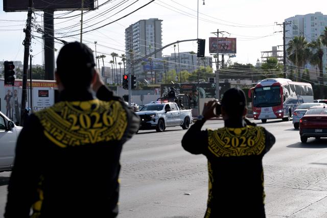Members of Mexico's National Guard record with their mobile phones the arrival of the bus transporting Iran's national football team at the Caliente Stadium for a training session in Tijuana, Mexico, on June 8, 2026, ahead of the FIFA 2026 World Cup football tournament. (Photo by Guillermo Arias / AFP)